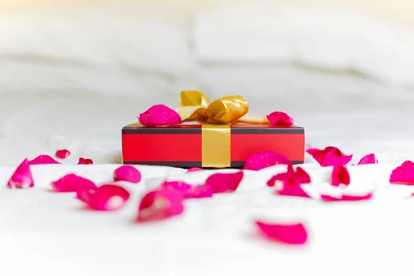 Gift or present box with rose petals on a bed. Holiday valentine's day concept. — Stock Photo, Image