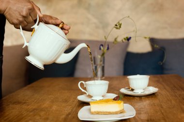Garson çay saatinde masaya limonlu cheesecake ile çay koyuyor..