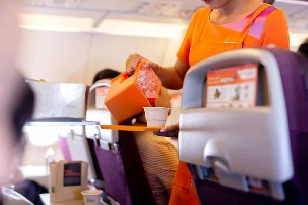Flight attendant serving drinks to passengers on board.