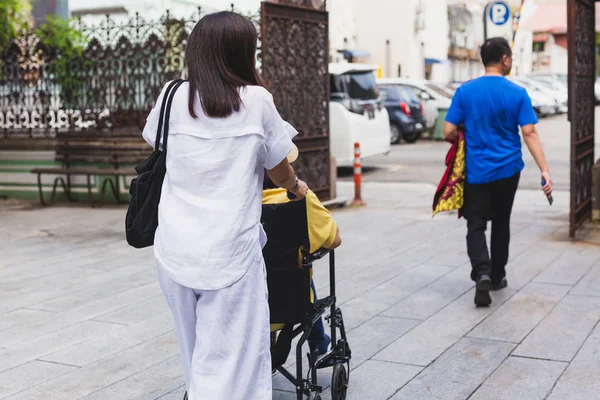 Filha levando sua mãe em cadeira de rodas para o lado vendo uma pequena cidade . — Fotografia de Stock