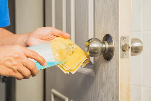 Hand cleaning door knob with alcohol and yellow microfiber cloth. Corona Virus infected protection