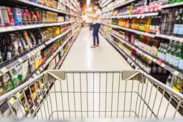 Süpermarkette alışveriş arabası koruyucu maskeli tüketiciler arka planda bulanık koronavirüs konseptiyle