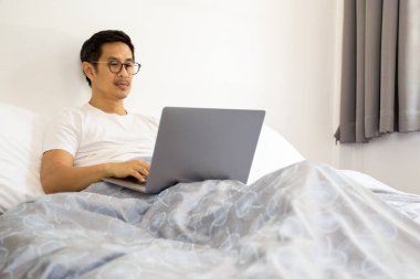 Gözlüklü yakışıklı adam evdeki covid-19 salgınında laptopta çalışıyor.