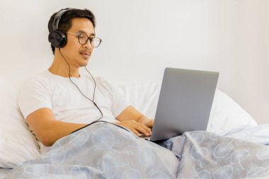 Kulaklıklı bir adam dizüstü bilgisayarla Coronavirus karantinasında çalışırken uyuyakalmış.