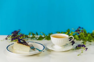 Bir dilim yanmış peynirli kek ve masada bir fincan çayla çay zamanı.