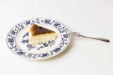 Beyaz arkaplanda ayrık çatallı Bask Yanmış Cheesecake