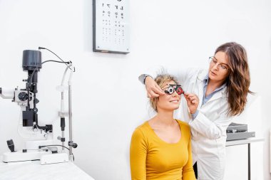 Young patient in optical clinic taking eye exam, looking at eye test chart clipart