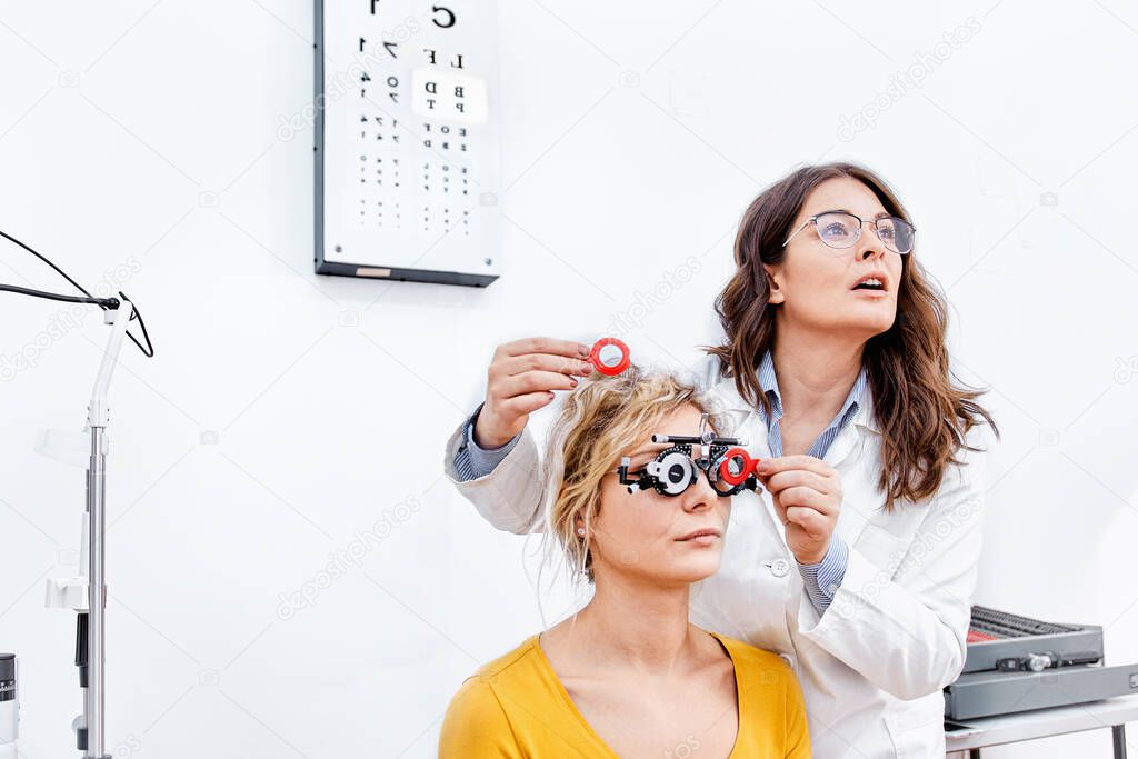 Young patient in optical clinic taking eye exam, looking at eye test chart