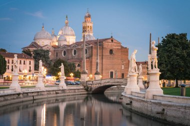 İtalya, Veneto, Padua 'daki Prato della Valle meydanında heykelleri olan Santa Giustina Bazilikası ve kanal manzarası