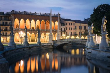 Padua 'daki Prato della Valle Meydanı. Kanal manzaralı heykeller, arka planda Loggia Amulea tipik bir Venedik neo-gotik sarayı, Veneto, İtalya