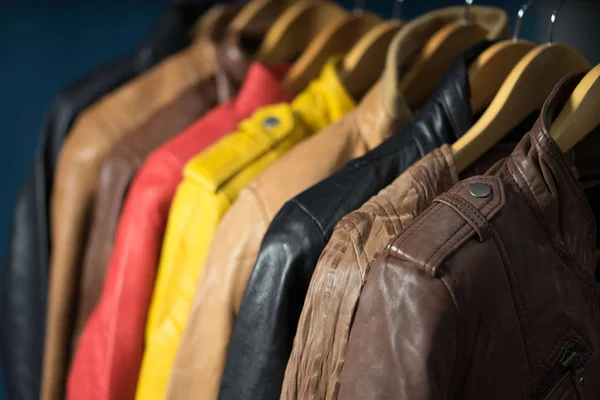 Különböző színű bőr kabát függesztett rack fehér háttér — Stock Fotó