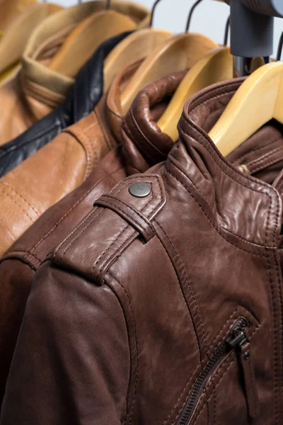 Jaqueta de couro de cor diferente pendurada no rack no fundo branco — Fotografia de Stock