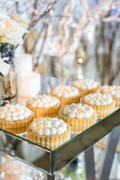 Cupcakes com creme branco na mesa decorado com flores brancas e velas — Fotografia de Stock