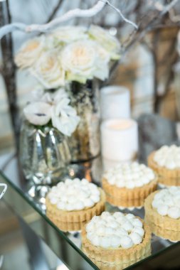 Masada beyaz krema ile cupcakes beyaz çiçekler ve mumlarla süslenmiş