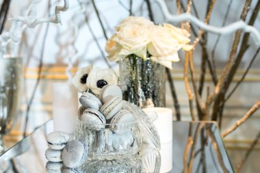 Macaroons masada bir vazoda güller ve mum ile dekore edilmiş 