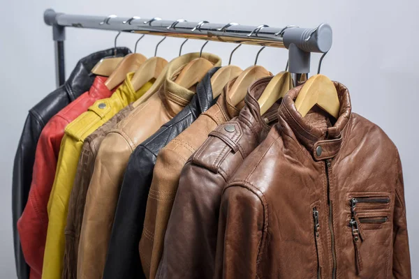 Farklı renk deri ceket raf beyaz arka plan üzerinde asılı