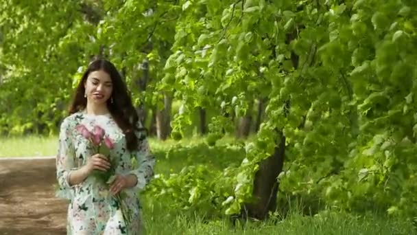 Menina morena elegante bonita com cabelos longos está posando na câmera com um buquê de rosas — Vídeo de Stock