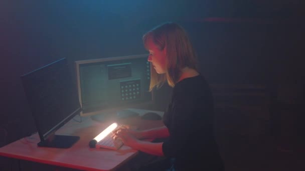 拥有金发的女黑客程序员在一个高科技行业工作 她在地下秘密地点周围都是展品数字电阻 霓虹灯在黑暗的房间里闪烁 — 图库视频影像