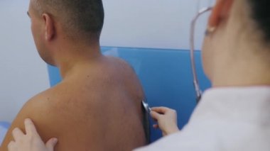 Doktor steteskopla hastanın vücudunu muayene eder, akciğerlerini ve kalbini dinler. Tüm vücut kontrolü. 