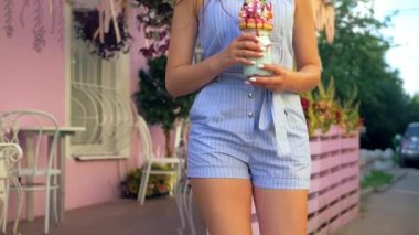 Güzel bir kadın yazın dışarıda vakit geçiriyor. Çekici kızın elinde çok katmanlı bir milkshake var. Renkli ve parlak bir içecek, tatlı bir tatlı.