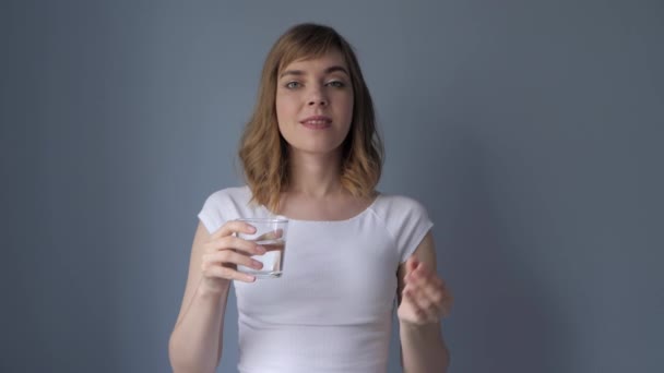 Aantrekkelijke vrouw slikt de pil, drinkt water. — Stockvideo