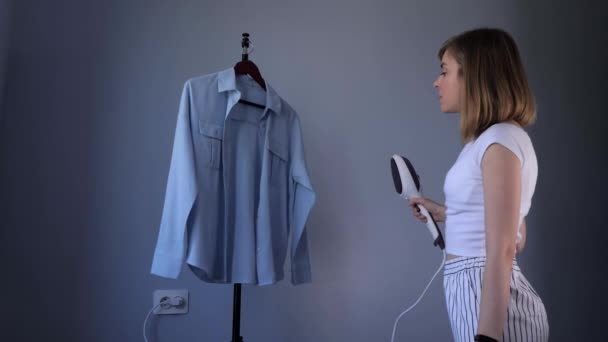 Mulher é vapor sua blusa em casa dentro de casa . — Vídeo de Stock