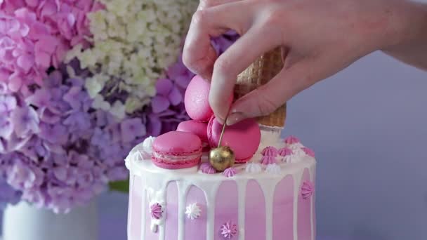 女孩从蛋糕层和从糕点袋中加入的白色奶油中烹调多层饼干蛋糕 后面是一束花 — 图库视频影像