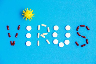 Coronavirüs tipografisi düzdü, covid-19. Mavi arka planda tablet ve haplardan yapılmış koronavirüs mektupları. 
