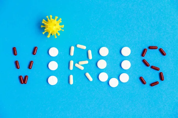 Flat lay typography of coronavirus, covid-19. Lettering of coronavirus made of tablets and pills on the blue background.