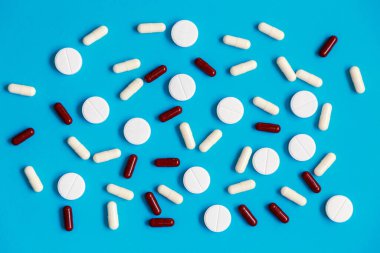 Mavi arka planda yatan hapların ve tabletlerin düz bir görüntüsü vardı. Sağlık tedavisi ya da ilaç. 