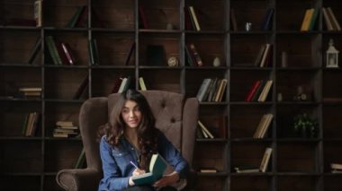 Genç çekici kadın kütüphanede günlüğü dolduruyor.