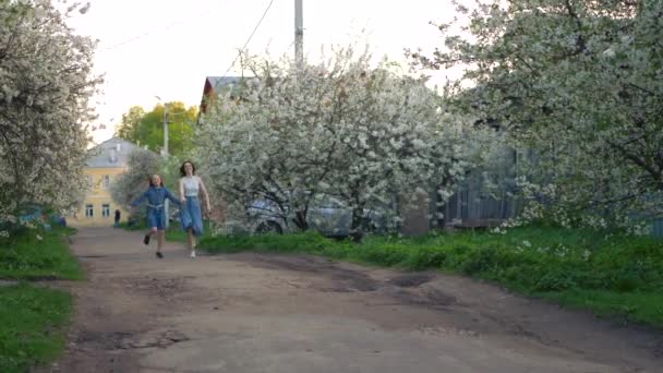 快乐的年轻家庭妈妈 孩子们在春天的大街上奔跑 健康的妈妈和小女孩喜欢手牵着手一起散步 — 图库视频影像