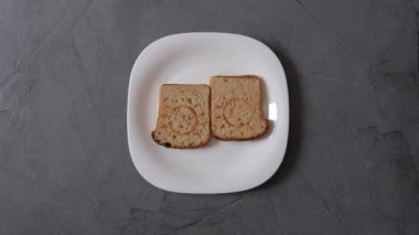 Beyaz tabakta sandviç yapma süreci. Gri arka plan. Sandviçler ekmek, yeşil salata yaprağı, kırmızı domates barışı, yumurta, sos ve yeşil soğandan yapılır.. 