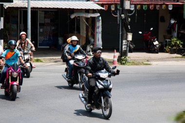 Asyalı vatandaşlar işe motosikletle giderler. Arka planda küçük yerel dükkanlar var. Phuket Tayland-04.03.2017.