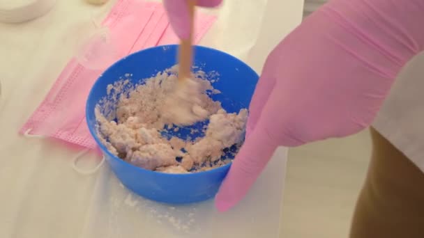 Cosmetoloog Mengt Alginaatmasker Kom Handen Roze Handschoenen Bereiding Schoonheidsmiddel — Stockvideo
