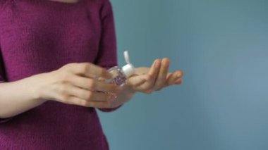 Temizleme, kadın ellerini dezenfekte etme süreci mavi arka planda bir dezenfektan yardımıyla.