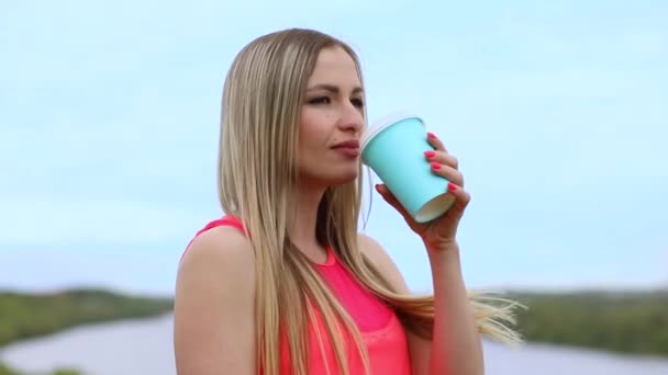 Attraktive athletische Mädchen trinkt Kaffee aus einem türkisfarbenen Glas. — Stockvideo