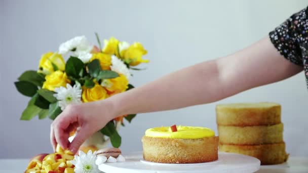 黄色のクリーム 果物の作品を使用して積層ケーキの充填を行います 作業スペースは テーブルの上に花や果物の充填の花束で飾られています — ストック動画