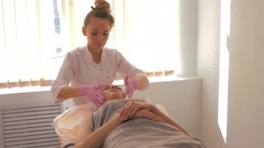 Kozmetik uzmanı, güzellik uzmanı hastaya yüz masajı yapıyor. Cilt bakımı ve sağlık tedavisi kavramı.