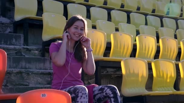 Молодая Спортсменка Слушает Музыку Расположен Стадионе Одета Розовую Футболку — стоковое видео