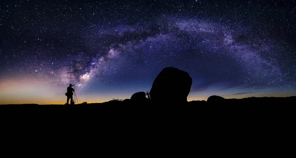 Astro fotograaf in een woestijn landschap met uitzicht van de Melkweg — Stockfoto