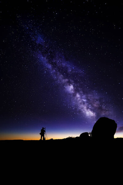 Astro Photographer in a Desert Landscape with view of Milky Way Galaxy