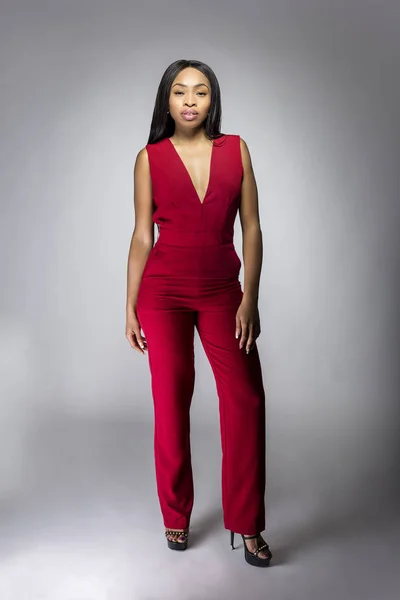 Black African female fashion model wearing red pantsuit for spring design.  The clothing looks semi formal or casual but elegant.  The image depits modern style trend.