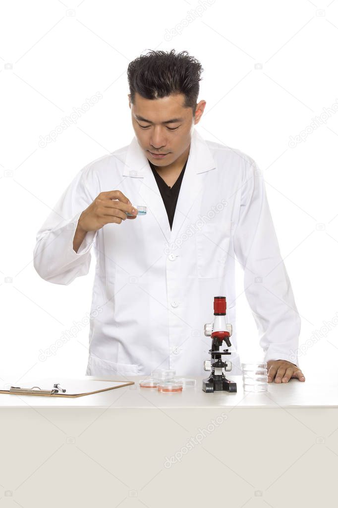 Asian male scientist or microbiologist studying research or experiments with a lab coat and microscope.  He is isolated on a white background.  The image depicts science and medical industry. 