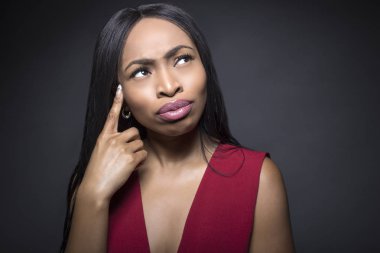 Siyah kadın model düşünce ile karanlık bir arka plan üzerinde veya karışık ifadeler.