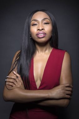 Kendinden emin ya da züppe ifadeleri ile karanlık bir arka plan üzerinde siyah kadın modeli.