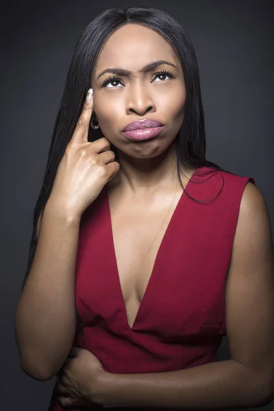Black female model on a dark background with thinking or confused expressions.