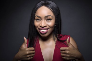 Onay ifadeleri ile karanlık bir arka plan üzerinde siyah kadın modeli. O onu başparmak dayanıyor.