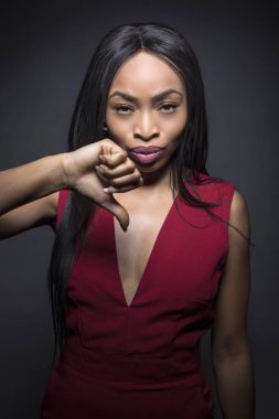 Ret ifadeleri ile karanlık bir arka plan üzerinde siyah kadın modeli. Onu başparmak aşağı onda.