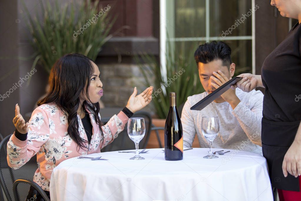 Couple on a date angry at a waitress in an outdoor restaurant.  They are upset and dissatisfied with the customer service or the food in the cafe.  The image depicts the food and service industry. 
